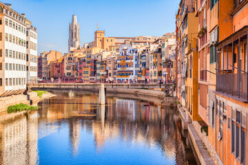 Girona, Spain - Medieval houses on the banks of the River Onyar, and the Pont de Sant Agusti, and the bell tower of Sant Feliu Collegiate Church, Girona, Catalonia, Spain. - obrazy, fototapety, plakaty