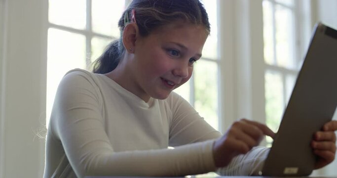 Girl child at table with smile on tablet for watching movies, online game or elearning with technology. Happy young kid in house with digital app for video streaming website, subscription and fun.