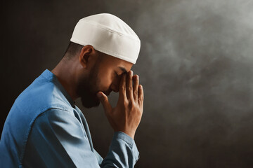 Portrait of sad crying young asian muslim man with beard praying on dark background - 739687244