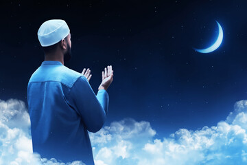 Back view of young asian muslim man with beard praying at blue night sky with stars and crescent moon - 739688033