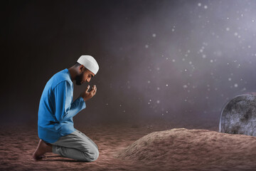 Portrait of sad crying young asian muslim man with beard praying on graveyard cemetery - 739689005