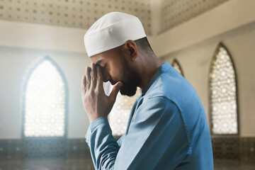 Portrait of sad crying young asian muslim man with beard praying in the mosque window arch - 739689202