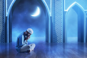 Young asian muslim man with beard praying in the mosque door arch at beautiful blue night sky with stars and moon - 739690254