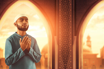 Portrait of handsome young asian muslim man with beard praise, thankful and relaxing in the mosque door arch at beautiful sunset sky - 739691264