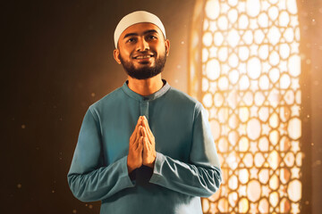 Portrait of handsome young asian muslim man with beard praise, thankful and smiling in the mosque window arch - 739691285