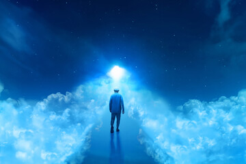 Back view of young arab man with beard on top, walking forward into shiny light alone over the cloud at beautiful blue night sky with stars - 739691889