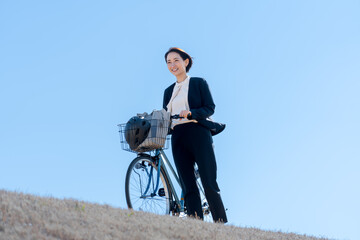 Naklejka premium 屋外で自転車をおすスーツを着た女性