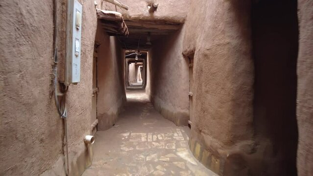 A camera moves through the mudbrick covered streets of Ushaiqer Heritage Village, Riyadh Province, Saudi Arabia. Accelerated video.