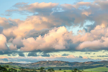 Billowing clouds drifting lazily across a pastel sky, casting soothing shadows over rolling hills