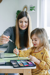 Parent Teaching Child to Paint with Watercolors