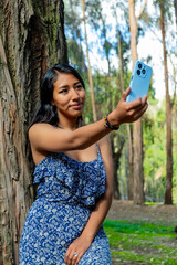 latin woman taking a selfie with her cellphone in a forest in bolivia - communication concept