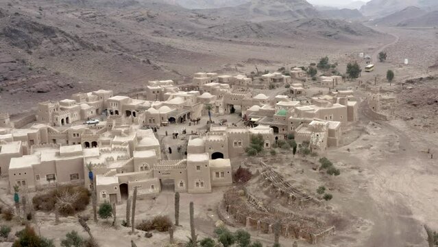 a drone shot of an old middle eastern town between mountains with a bazaar full of people. middle east, arab, city, town 500 ad, iraq, iran, ancient, 4k, madina