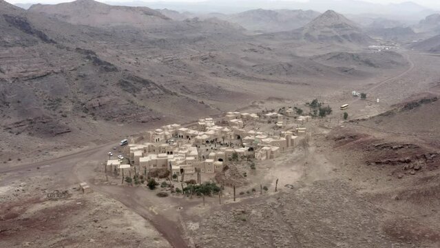 a drone shot of an old middle eastern town between mountains with a bazaar full of people. middle east, arab, city, town 500 ad, iraq, iran, ancient, 4k, madina