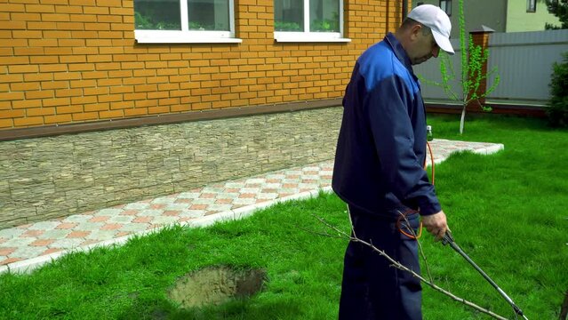 A man works in the garden, spraying weeds from a sprayer