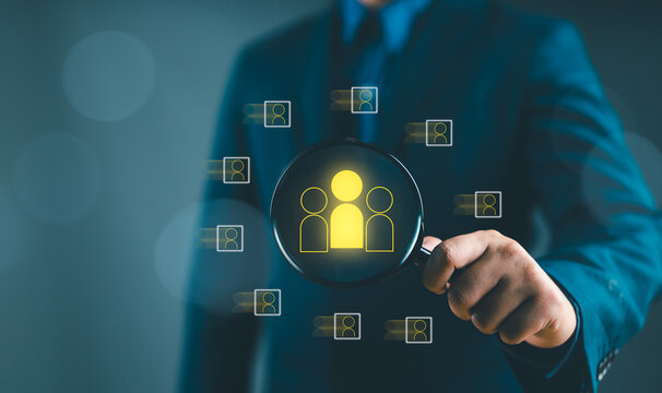 Human Resource Management, HRM, Businessman holding magnifier for searching to human icons for human development and recruitment concept. Customer Relationship Management, customer network technology