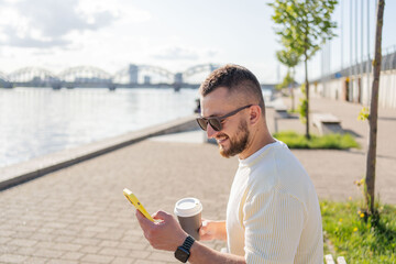 man using mobile phone text messaging on the street. Hipster guy shopping online. Man holding mobile phone reading text message, communication online on the street.