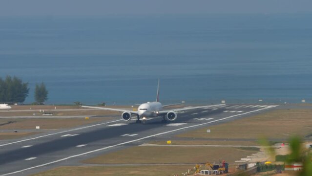 Wide-body passenger airliner speeding up for takeoff. Sea in the background