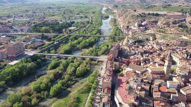 Picturesque spring aerial view of Fraga cityscape overlooking two neighborhoods - historic El casco and contemporary Las Afueras on banks of Cinca river on sunny day, Spain