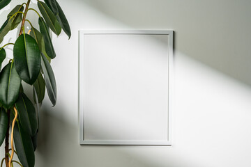 White wooden photo frame with plant leaves on white background