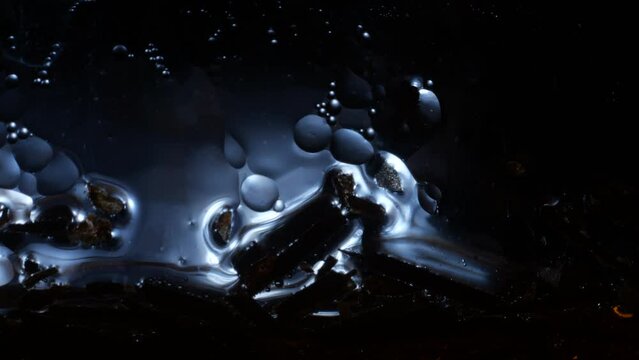 Ice cold liquid with cell like bubbles of oil moving slowly. Static background.