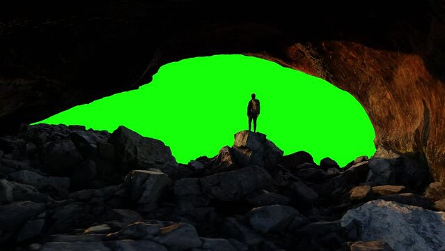 Adventure Man Hiker standing, looking out in Rocky cave on top of Mountain. Composite Cutout with Green Screen Background.