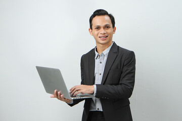 Happy asian indonesian business man in suit holding laptop computer on isolated background