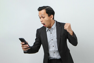 angry mad asian indonesian business man in suit holding smart phone on isolated background