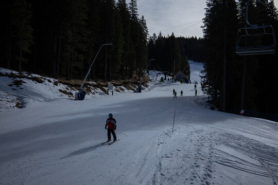 Skiing on rogla middle track. Ski slope of rogla, with visible cable ropeway in the background, some skiers on the slopes. Cold winter day with some sun. View from the cable car.
