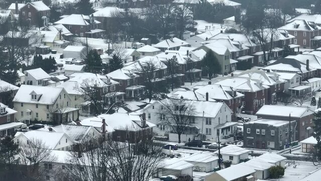 Aerial shot of a suburban neighborhood in the USA. Snowy winter environment with many houses.