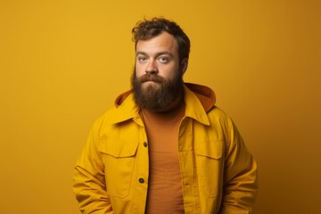 Obraz premium Portrait of a bearded man in a yellow jacket on a yellow background.