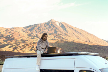 Young Man Working on Laptop Atop Van With Teide Mountain in Background