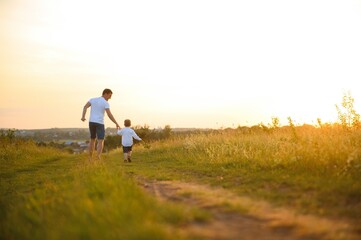 Happy father, son child running playing in the park outdoors together. Family, Father's Day, parenting, active lifestyle concept.
