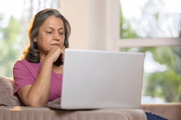 Senior woman using laptop on sofa at home