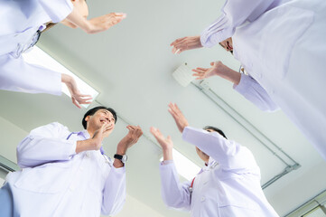A delighted doctor team enjoying achievement in a hospital setting with clap hands.
