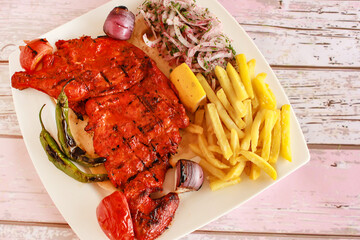 HALF GRILLED TANDOORI CHICKEN with lemon, onion and french fries served in dish isolated wooden table top view of tandoori grill bbq food
