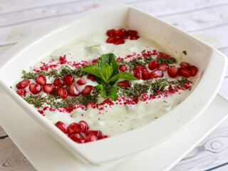 Mast O khiar or Persian Yogurt Dip with mint leave and pomegranate seeds Raita served in dish isolated on wooden table top view of cold mazza arabic food