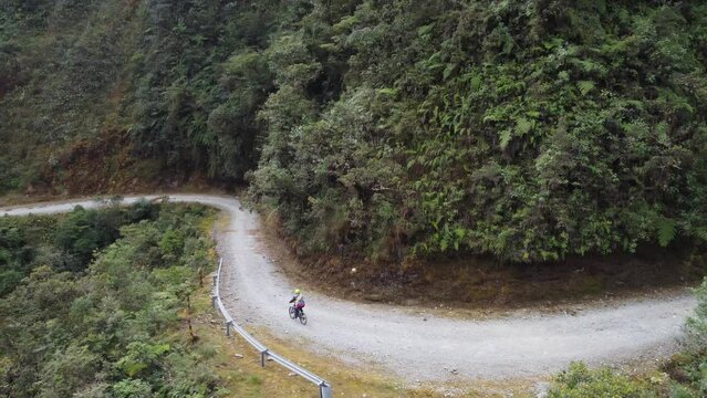 Aerial: Cyclist rides bike on famous Yungas Death Road in Bolivia mtns