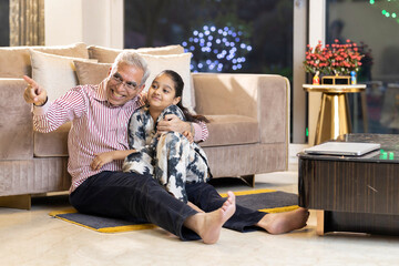 Loving grandfather tickling granddaughter and having fun at home