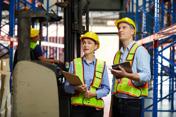 factory workers looking for checking product and holding clipboard in the warehouse storage
