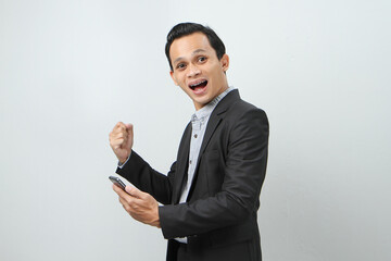 happy asian indonesian business man in suit holding smart phone on isolated background
