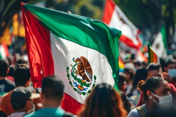 The Mexican flag prominently displayed among a crowd of people at a cultural or national event.