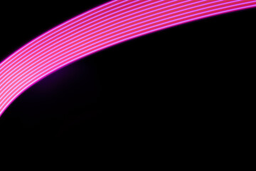 Pink and purple shining neon curved line of light as arc with smooth stripes on black background. Abstract background with energy line in motion, light painting in futuristic style.
