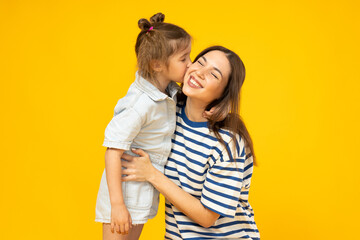 Mother and daughter pose for a photo on a yellow background.