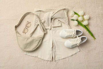 Spring light female outfit and flowers on beige background, top view