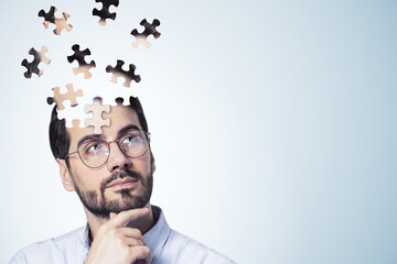 Puzzle headed thoughtful businessman portrait on light background with mock up place. Solution, decision and brainstorm concept. - obrazy, fototapety, plakaty