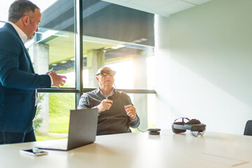 Businessman talking with client during a demo of vr goggles
