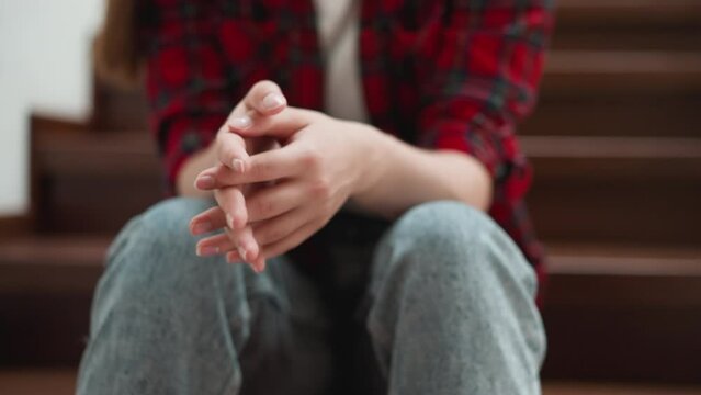 Woman rubs palms sitting on steps closeup. Girlfriend prepares to breakup with abusive boyfriend on staircase. Nervous lady deals with panic attack