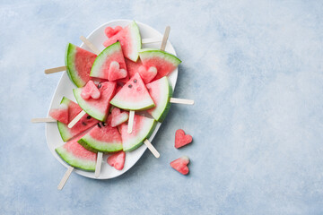 Watermelon slice popsicles on a blue background. Copy space, top view.