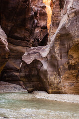 Jordan. Miracle of nature - Wadi el-Mujib gorge. Mesmerizing beauty of multi-colored steep cliffs of canyon. Along bottom of narrow gorge, among rock formations, flows unusually beautiful river,.