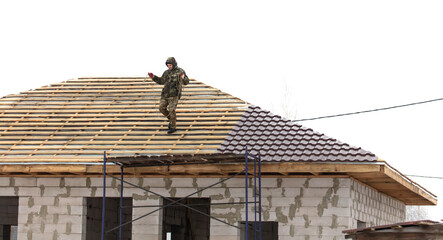 Workers install tiles on the roof of a house in winter
